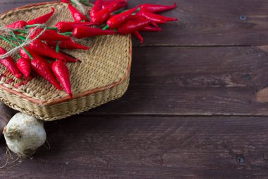 Biber ve sarımsak ahşap bir arka plan üzerinde hasır bir kapta