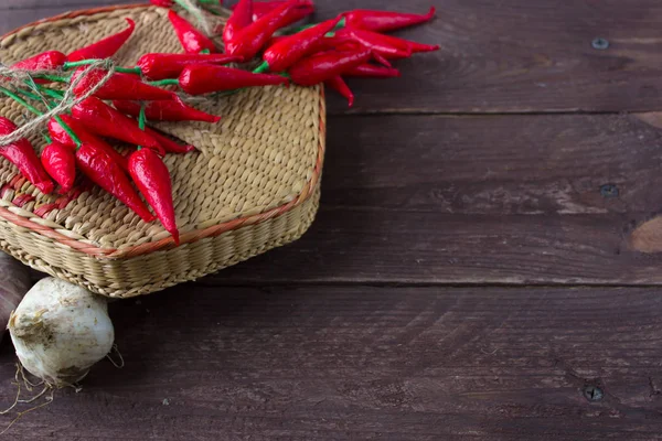 Biber ve sarımsak ahşap bir arka plan üzerinde hasır bir kapta