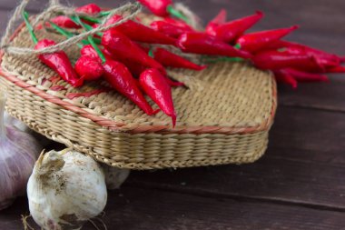 Biber ve sarımsak ahşap bir arka plan üzerinde hasır bir kapta