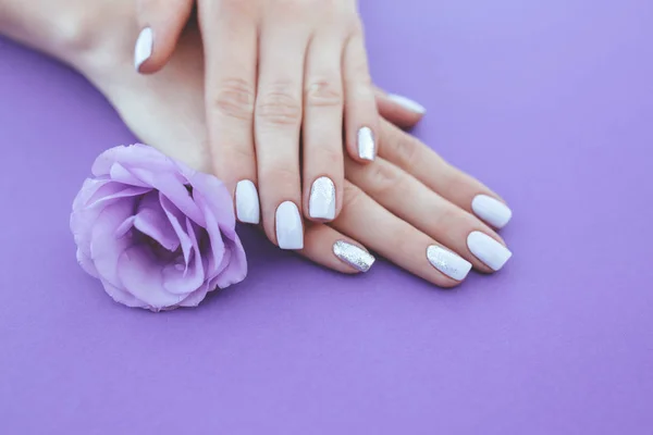 Manicura púrpura sobre fondo liso con una flor . — Foto de Stock