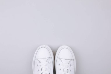 Gri arka planda beyaz spor ayakkabılar.
