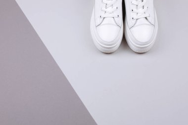 Gri arka planda beyaz spor ayakkabılar.