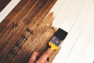 Adam ahşap bir yüzeyi koyu boyayla boyar. Arka plan.