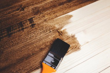 Adam ahşap bir yüzeyi koyu boyayla boyar. Arka plan.