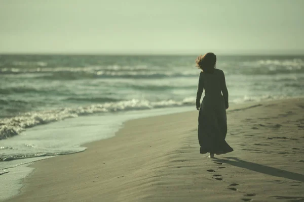 Hermosa joven camina a lo largo del oleaje en una playa de arena prístina — Foto de Stock