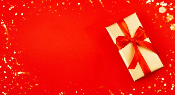 Золотая подарочная коробка с красным бантом на красном фоне. Концепция Нового года . — стоковое фото