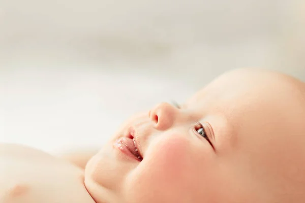 Beautiful baby lies on bed smiling — Stock Photo, Image
