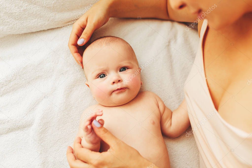 young beautiful mother lies with the baby on the bed, gently kisses, sleeping together