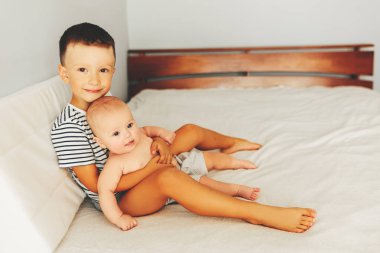 güzel bebek ağabeyi ile yatakta yatıyor. Çocuk küçük kız kardeşini öper..