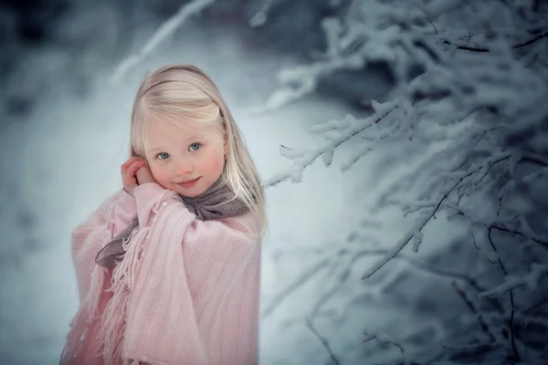 Okouzlující, roztomilá holčička v růžovém svetru ve sněžném zimním lese. — Stock fotografie