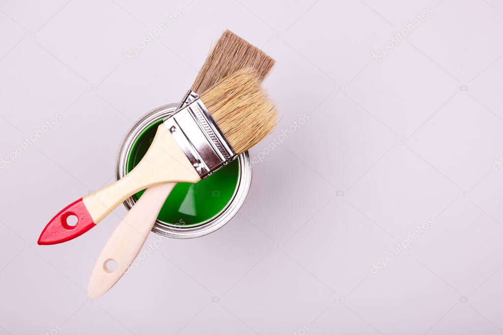brushes and an open can with red on plain gray background