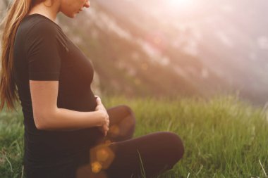 Hamile kız, dağlarda, parkta ya da dışarıda yoga ya da meditasyon yapıyor..