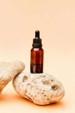 Çay yağıyla güzel bir kompozisyon. Cam kozmetik şişeleri parlak güneş ışığıyla bej bir arka planda bir taşın üzerinde duruyor. Doğal kozmetik konsepti, doğal gerekli petrol.