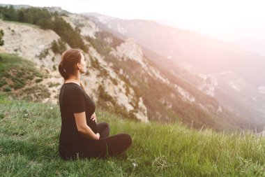 Hamile kız, dağlarda, parkta ya da dışarıda yoga ya da meditasyon yapıyor..