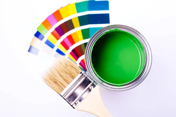 Pincel de pintura que pone en un montón de muestras de color. lata abierta de pintura verde —  Fotos de Stock