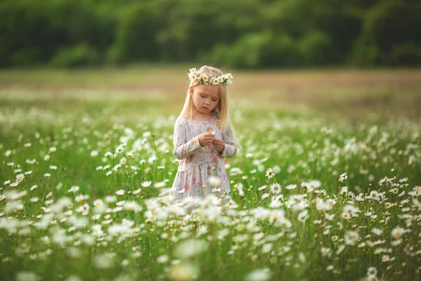 Malá krásná holčička běží po ulici nebo v parku a směje se, přes pole. západ slunce, dětství. Emocionální portrét šťastné a laskavé dívky s vlnitými vlasy při pohledu s úsměvem — Stock fotografie