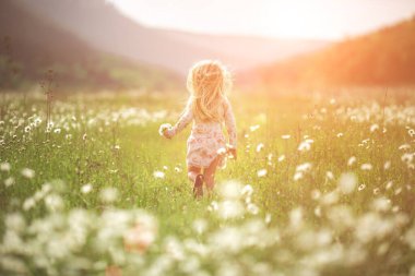 Küçük güzel kız sokakta ya da parkta koşar, gülerek, tarlanın karşısına geçer. Gün batımı ışığı, çocukluk. Mutlu ve nazik bir kızın duygusal portresi dalgalı saçlarıyla gülümserken