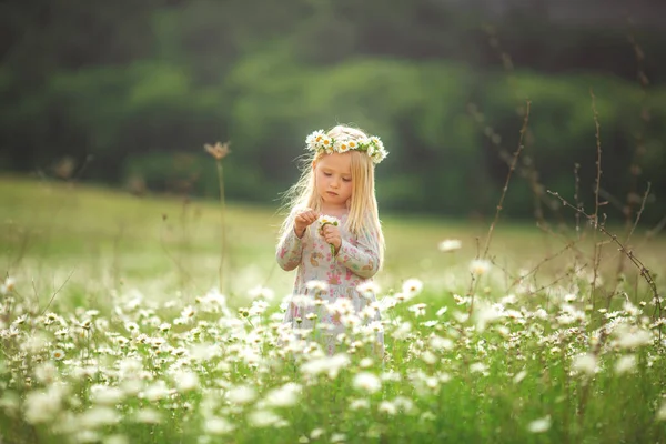 Klein mooi meisje rent op straat of in het park lachend, over het veld. zonsondergang licht, kindertijd. Emotioneel portret van een gelukkig en vriendelijk meisje met golvend haar op zoek met een glimlach, terwijl — Stockfoto