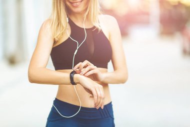 Su telefonu ve spor minderiyle genç atletik kadın dışarıda spor yapıyor.