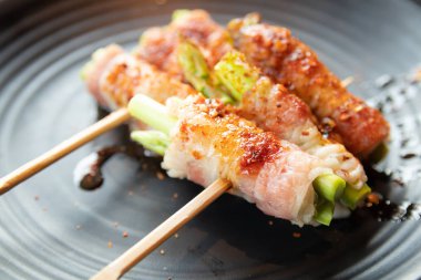 Pastırma kuşkonmaz şiş siyah çanak üzerinde sarılmış.