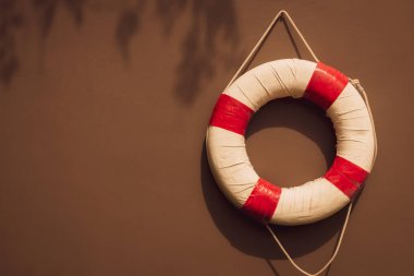 kahverengi duvara asılı kırmızı ve beyaz güvenlik torus veya cankurtaran şamandırası