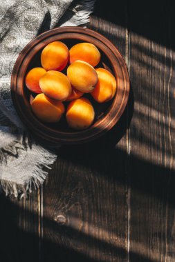 Ahşap masa üzerinde bir seramik kase olgun kayısı.