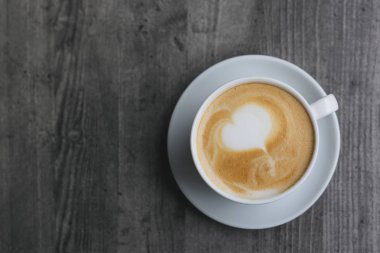 Ahşap arka planda latte sanatı ile kahve fincanı. Metin için yer.