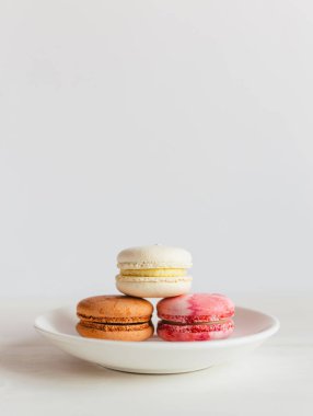 Beyaz tabakta üç Fransız makarnası. Minimal kavram, metin yeri.