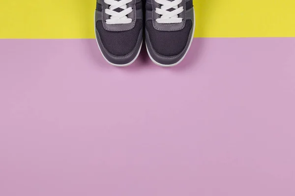 Sneakers grigie sullo sfondo giallo e viola. Concetto per uno stile di vita sano e allenamento quotidiano . — Foto Stock