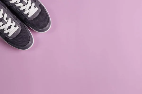 Grå sneakers på violett bakgrund. Koncept för hälsosam livsstil och vardagsträning. — Stockfoto