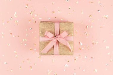 Altın ve gümüş ışıltılar ile pembe arka plan üzerinde pembe yay ile Altın hediye kutusu. 