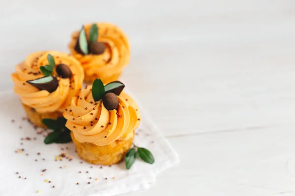Sabrosos cupcakes de calabaza con crema de naranja y decoración en mesa de madera blanca . — Foto de Stock