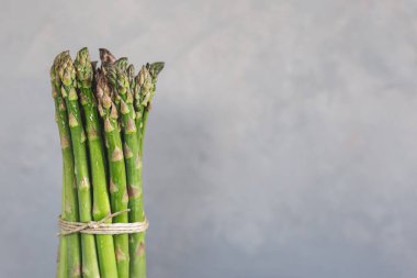 Gri arka planda bir sürü taze kuşkonmaz. Metin için yer.