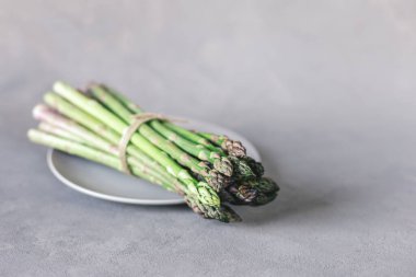 Gri arka planda bir sürü taze kuşkonmaz. Metin için yer.