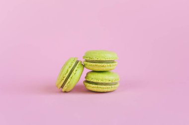Pembe pastel arka planda açık yeşil Fransız kurabiyeleri. Metin için yer.