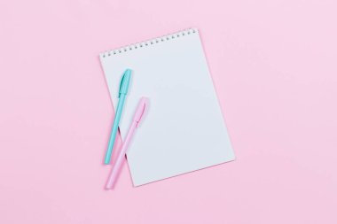 Boş sayfası olan bir defter ve pembe arka planda iki kalem. Düz yatıyordu. Metin için yer. 