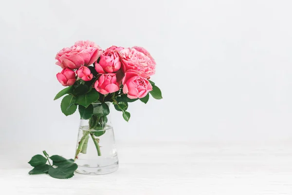 Romantic bouquet of pink roses in a glass vase on a white background.  Place for text.