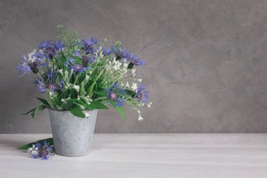 Gri bir arka planda eski bir saksıda romantik bir buket çiçek. Metin için yer.