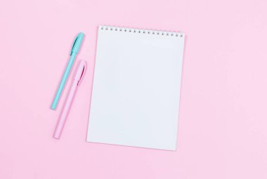Boş sayfası olan bir defter ve pembe arka planda iki kalem. Düz yatıyordu. Metin için yer. 