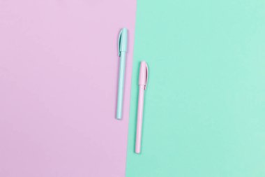 Menekşe ve turkuaz arka planda iki kalem. Düz yatıyordu. Metin için yer. 