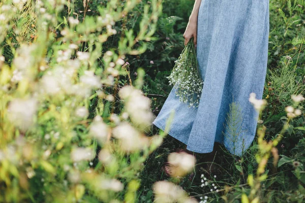 太陽の光の下で夏の牧草地に野花の束を持つライトブルーのリネンのドレスの女の子 夏の背景 — ストック写真