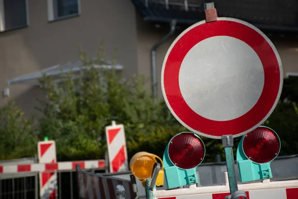 Kırmızı yuvarlak yol tabelası. Yansıtıcı ışıkları ve barikatları var. İnşaat çalışmaları nedeniyle oturma alanındaki caddeyi kapatıyorlar.