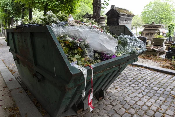 A dumpster filled with discarded flower arrangements that were left behind on graves from visitors at a cemetery. — Stock Photo, Image