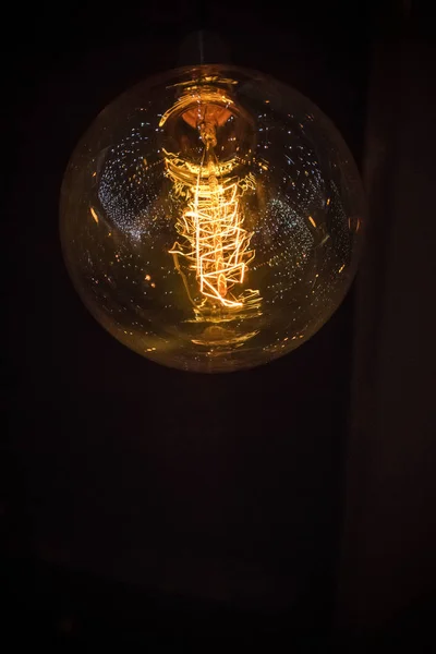 A close-up of a light bulb in the dark with decorative lights reflecting in it