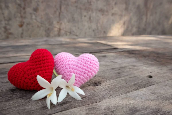 Tejer corazones rojos y rosados con Millintonia blanca en la mesa de madera rugosa. El fondo de la pared de roca con luz solar. Copiar espacio para editar — Foto de Stock