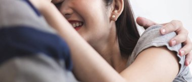 Genç Asyalı çift sarılıyor ya da sarılıyor. Aşığın mutlu ilişkisi. Erkek, yatak odasında bir kadını öpüyor ve sarılıyor. Sevgili sevgili ve sevgili arasındaki güzel romantik bağ.