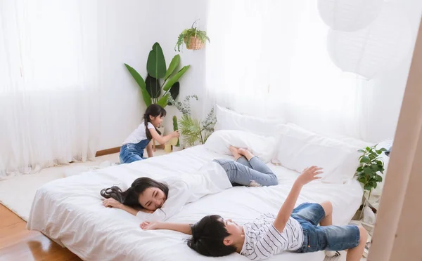 Lovely happy Asian family at cozy home. Smiling mother, son and daughter enjoy ,relax and playful together in bedroom. Happiness relationship and bonding of love between parent and children moment