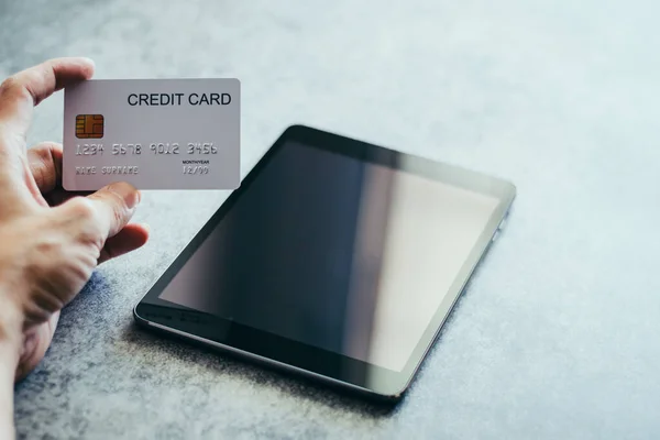 Tabletle el ele tutuşan kredi kartı. E-ticaret ya da e-ticaret çevrimiçi alışveriş ve ödeme. Siber uzayda ticaret için dijital para transferi. İş ve finans kavramı.