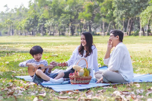 Mutlu Asyalı aile hafta sonları ya da tatillerde parkta boş vakit geçirir. Anne ve sağlıklı büyükanne çocuk, oğul ya da torunun gitar çalmasından hoşlanırlar. Aile üretimi ilişkisi ya da fotoğraf konsepti