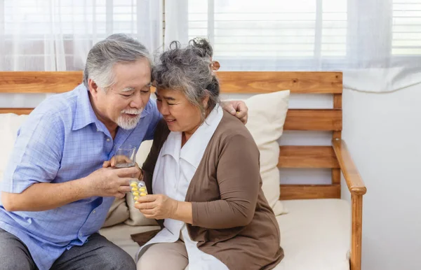 Asian couple woman caring sick elderly man by giving pill or drug at home. Love and relationship of retired senior couple. Health care and medicine of illness aged people photo concept.